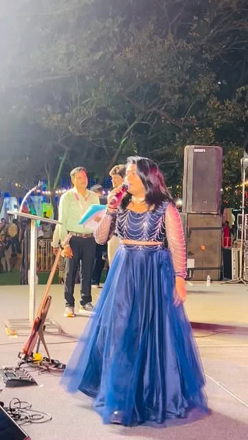 Reena hosting on stage in a blue gown at Audisankara Mahotsav in Gudur